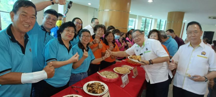 古晋南市市长拿督黄鸿圣品尝诏安美食及和妇女组成员合照。