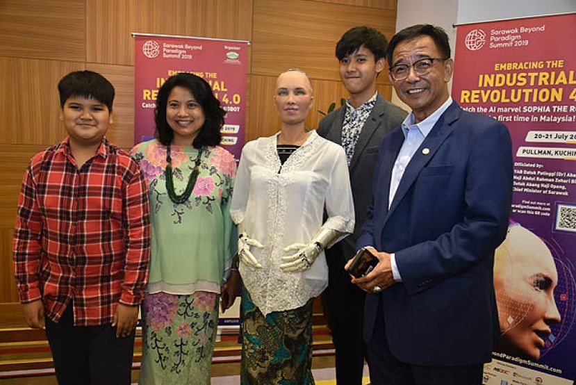 砂旅游、艺术、文化、青年与体育部长拿督阿都卡林（右一）与家人和机械人索菲亚合照。