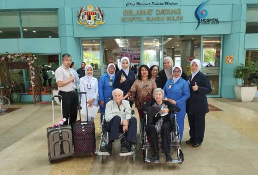 患上新冠肺炎而治愈的美籍妇女（前右）与丈夫一起出院时，在双溪毛糯医院病楼前与医护人员合摄。