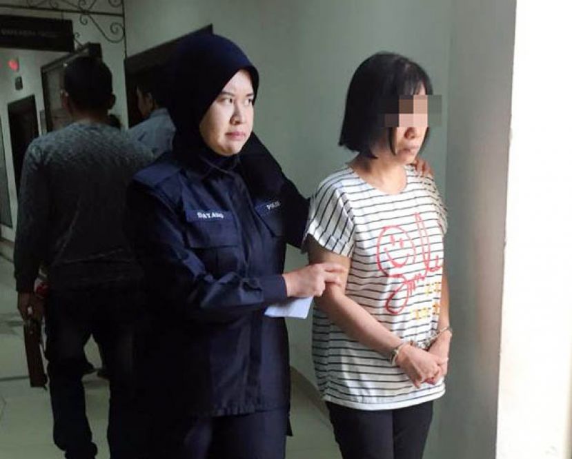 在超市被发现涉嫌拥有1张20令吉面额假钞的中年妇女，在过堂后被押离开法庭时摄。