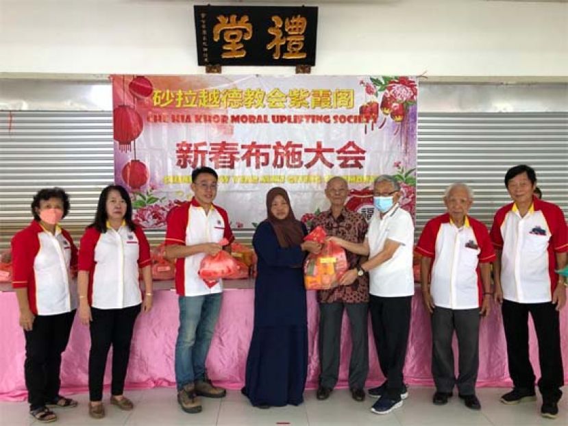 砂拉越德教会紫霞阁名誉阁长王昌隆及杨维堃（右三及右四）移交布施品于其中一户家庭，左起为该阁妇女主任林嫦凤、署理阁长房秀芳、新春布施小组主任陈梦仁，右起为该阁副阁长黄纪清及贝清俊。
