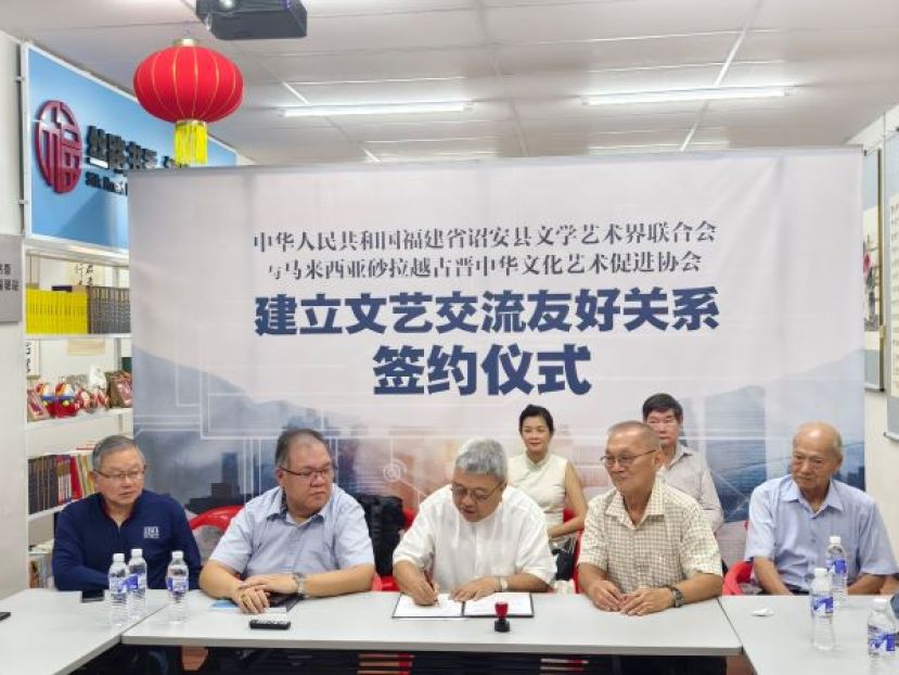 在马来西亚古晋中华书画研究会会长田荣喜（左一）、马来西亚砂拉越-中国友好协会常务副会长拿督黄国辉（左二）以及马来西亚砂拉越华文作家协会会长李福安（右一）和马来西亚古晋中华文化艺术促进协会名誉会长陈华敏（右二）的见证下，马来西亚古晋中华文化艺术促进协会会长许庆喜（中）签署协议时影。