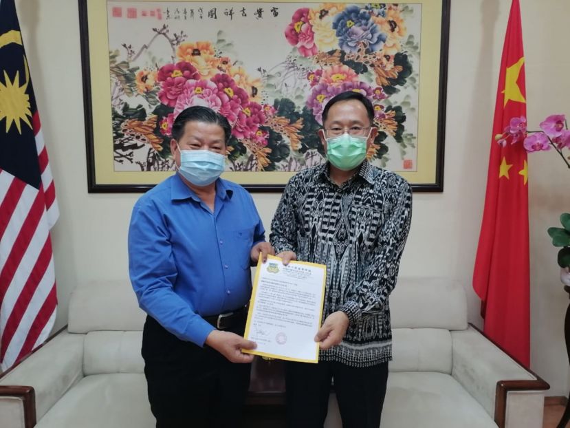 砂医总会长江宗兴（左）移交邀亚洲中医技职学院多届毕业生毕业千人宴担任上宾函件予中国驻古晋总领事邢伟平。