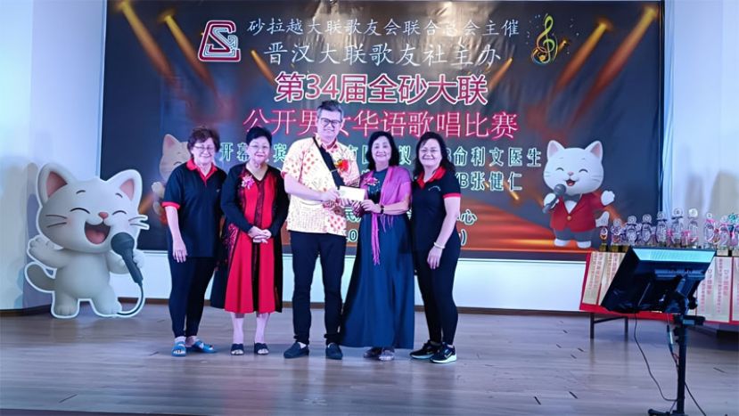 古晋市国会议员俞利文（中）现场移交拨款支票予大会会长兼晋汉大联歌友社社长黄碧莺（右二）。左起为筹备会秘书余悦凤女士，筹备会主席叶玉翠女士；右为理事官侑郿。