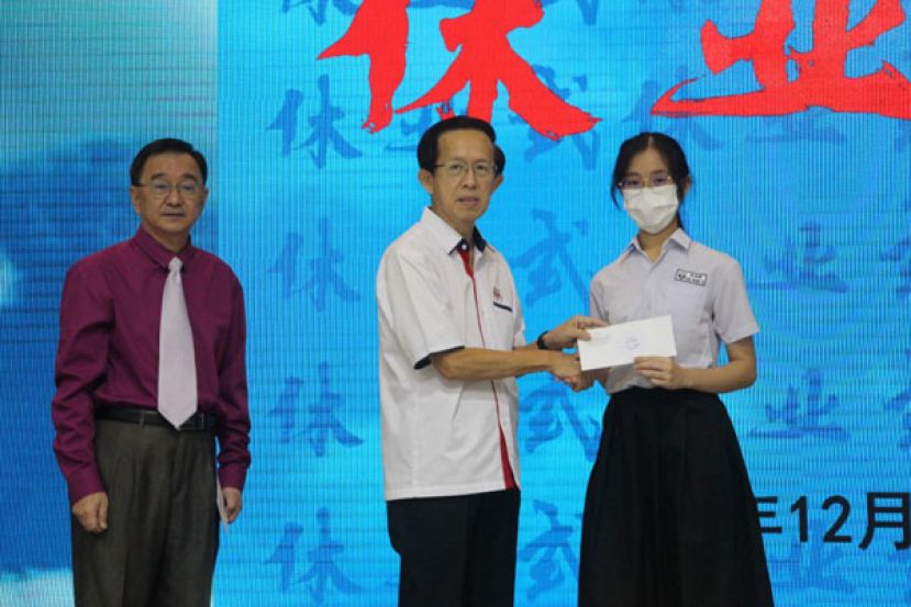 古晋中中校董副主席郑佑上（中）移交学优特优奖给获奖的学生；左为一中校长叶宗元。