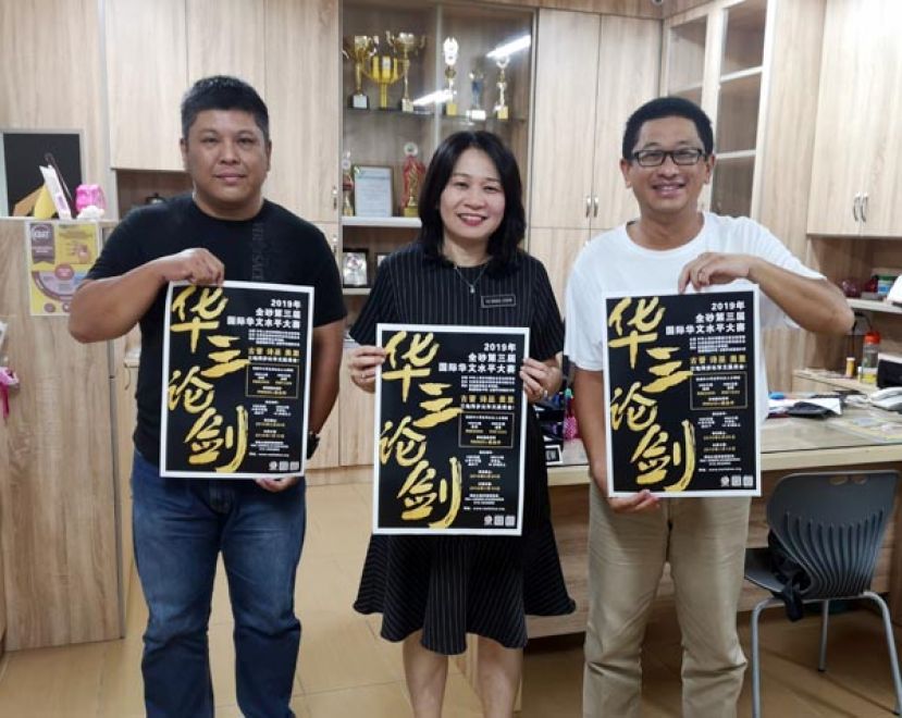 留华砂总总会长黄首詠（右）和署理会长曹斌超（左）移交&ldquo;第三届全砂华文水平大赛-华三论剑&rdquo;海报予敦化小学余祥秋校长。敦化小学今年派出十三位学生组队参赛。