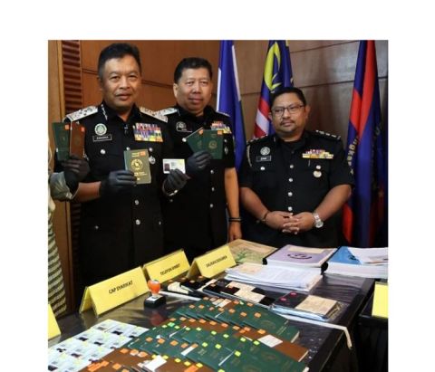 移民局总监扎卡利雅(左一)展示所起获的各国护照等。