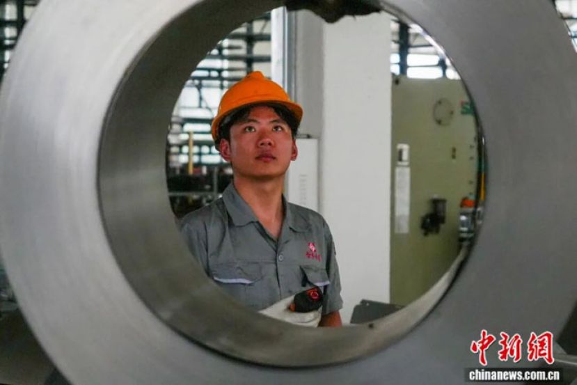 钢制家具企业生产车间内，工作人员吊运生产所需的钢卷。
