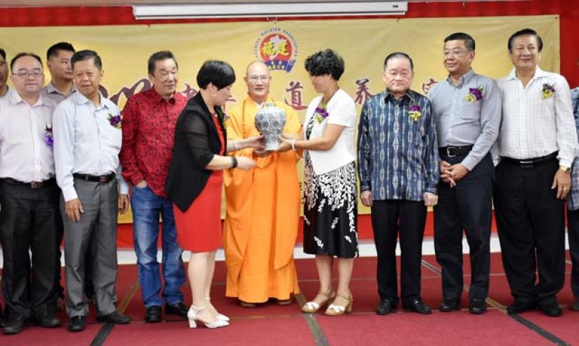 福建省政协常委、福建佛学院院长、福州开元寺方丈本性禅师（左五）赠送纪念品予中国驻古晋总领事程广中夫人高翠莲教授（右四）。