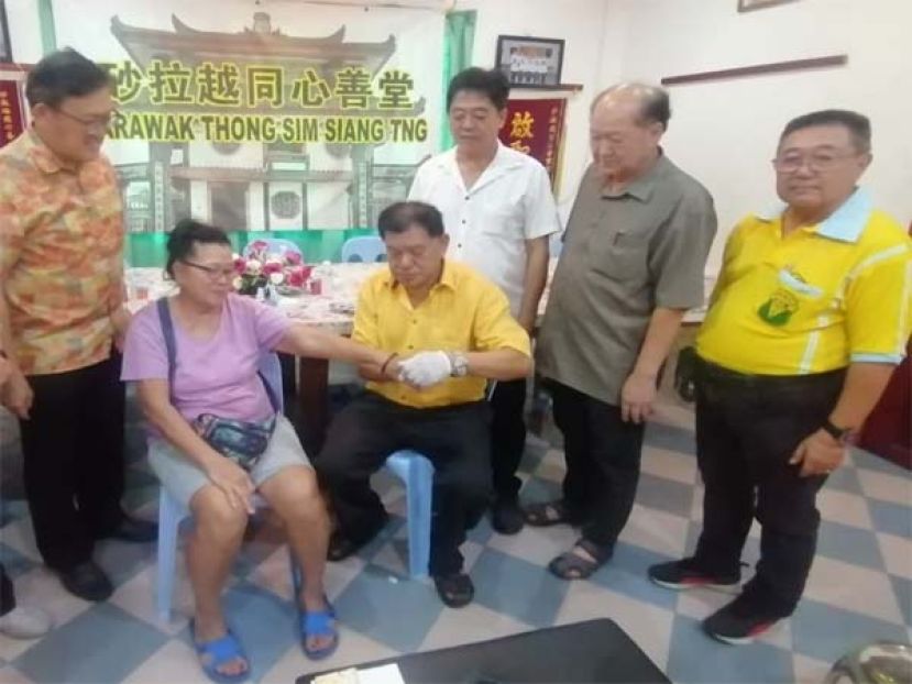 薛华东（左）同李汉标（左起）、黄国远及许义华观看义诊筹委主席陈中兴为一民众做推拿针灸。