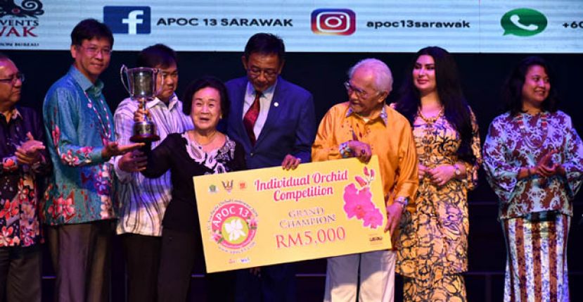 砂州元首敦泰益玛目（右三）颁发个人组全场总冠军奖项予古晋胡姬业者林拿汀许桂珍（左四）与其儿子欧阳健仁（左三）。