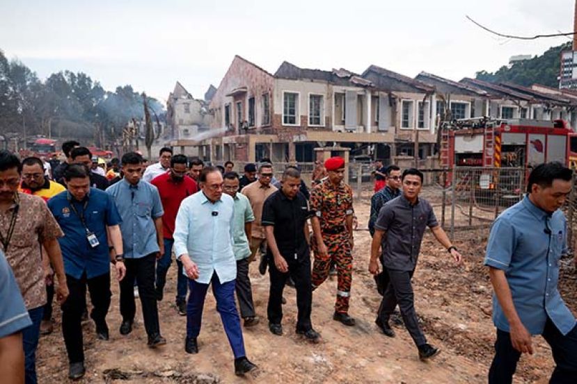 ●首相安华（前中）巡视灾场聆听汇报，身后为严重受损的房屋，满目疮痍。