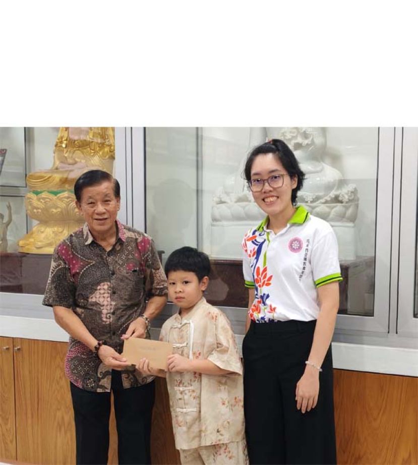 在马佛青砂拉越联委会主席余莹洁（右）的陪同下，古晋慈云佛教正信会主席萧乃文颁奖予低年级组冠军得主曾宇晨（古晋慈云佛教正信会）时影。
