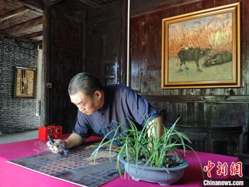 安福县枫田镇车田旅游新村烙画馆内，刘继龙正在烙画。