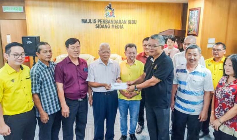 诗巫市议会主席丁永豪（右3）在砂地方政府与房屋部长拿督斯里沈桂贤（右4）等人见证下，颁发市集清洁承包工程予诗巫省暨马拉端县小贩联合会主席蒋祥源。