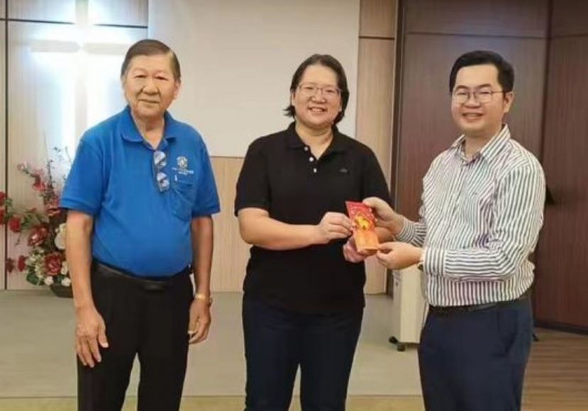砂医总副会长江邦忠（右）由锡安堂牧师刘惠清手中接过红包；左为该堂乐龄团契主席赵仕庆。