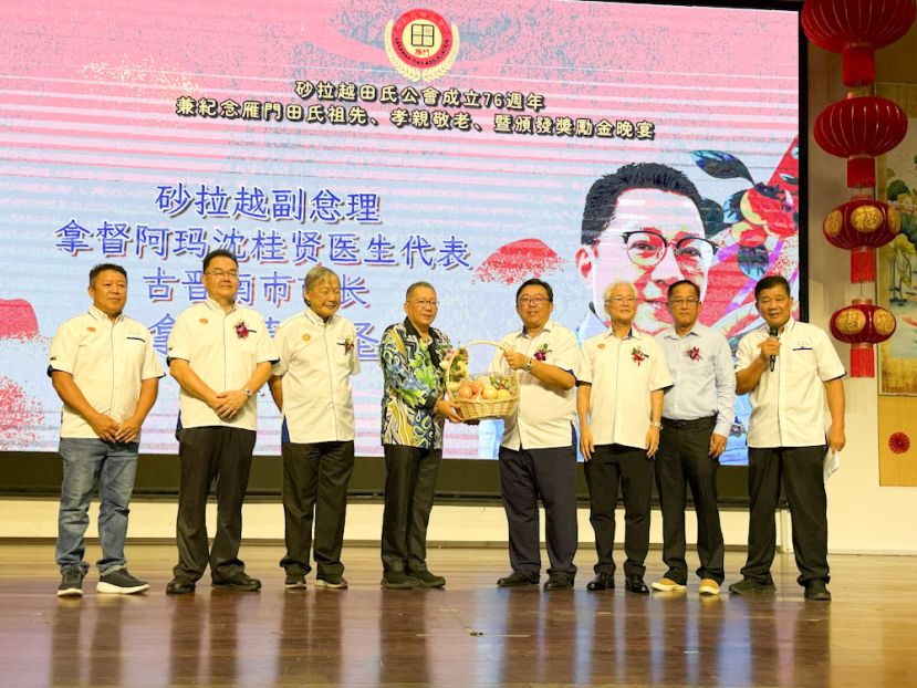 筹委会主席田志祥（右四）赠送纪念品给古晋南市市长拿督黄鸿圣（左四）。左起为砂拉越田氏公会副财政田林坚、副主席田松茂及主席田锡川；右起为秘书田福星、顾问田添保及副主席本固鲁田新华。