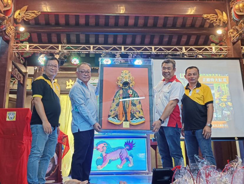 古晋潮州公会会长周文盛（右二）移交标价3万1888令吉的玄天上帝帝冠与披袍竞标者陈瑞兴（左二）。左一是标物晚宴筹委会主席郭景盛、右一是古晋上帝庙保委员会神事组主任李顺隆。