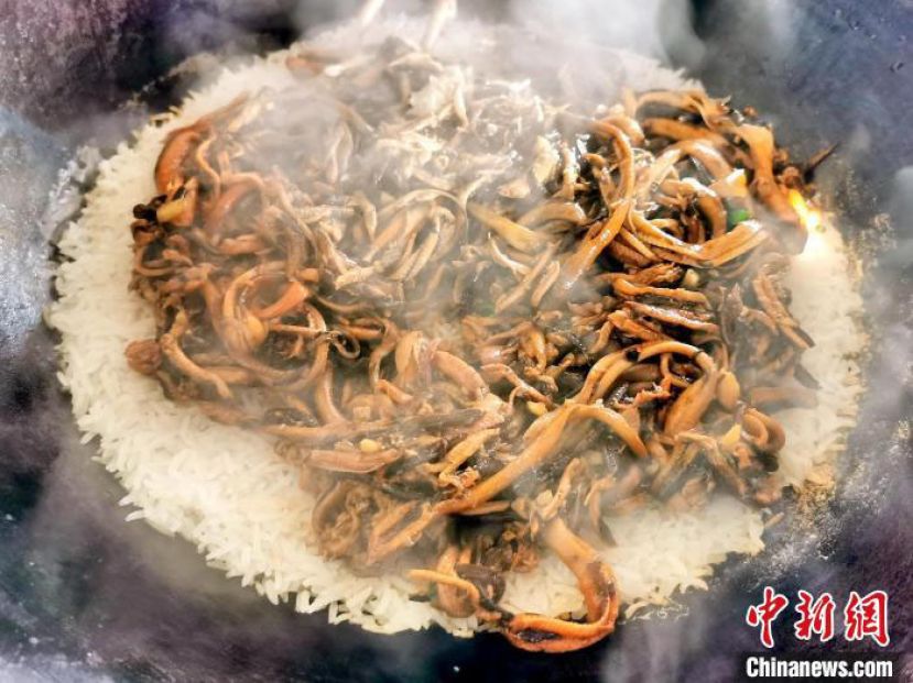 将炒好的黄鳝肉丝平铺在即将煮熟的米饭上。