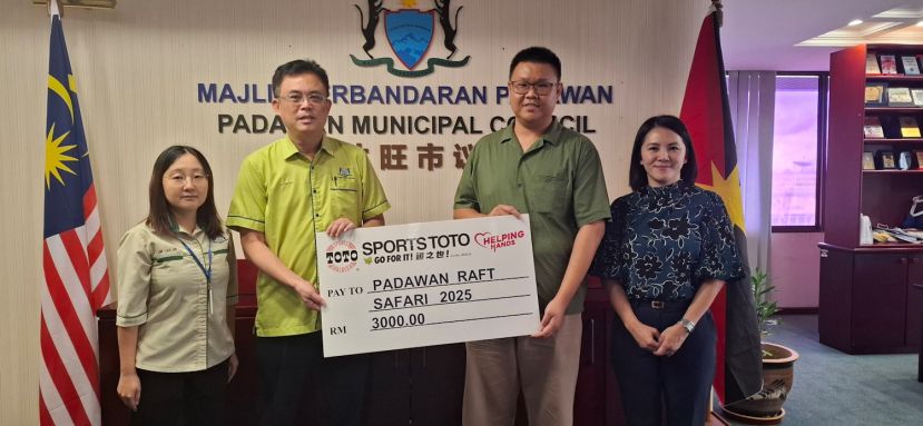 大马多多博彩有限公司（砂拉越）助理区域经理刘师铭（右二）移交3000令吉模拟支票予巴达旺市议会主席陈开（左二），右一为大马多多博彩有限公司古晋A区销售执行员吕奕豫。