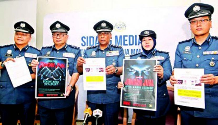 图：苏博玛廉（中）展示派发给商店的拒绝售卖走私烟酒店海报。