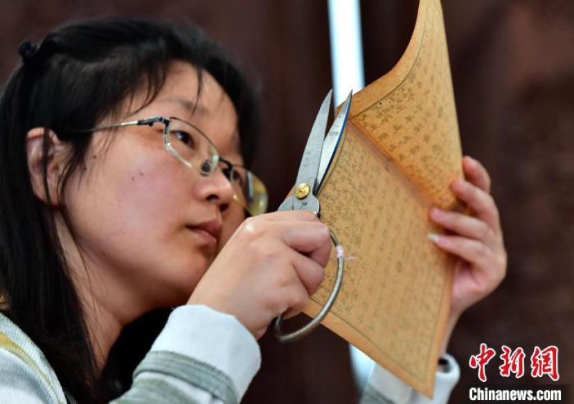 &ldquo;90后&rdquo;古籍修复师吴钰正在剪齐修复后的书叶补茬。