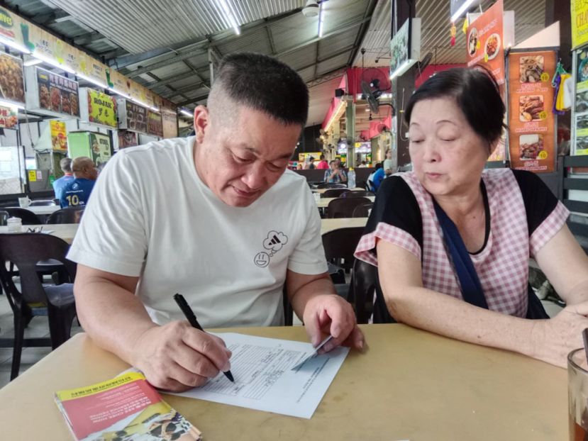 巴都林当区议员施志豪（左）协助年长者申请砂政府"年长者健康福利计划"（SCHB）。