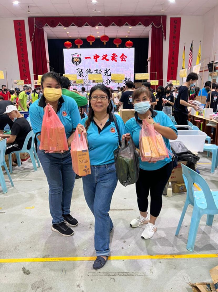 砂拉越诏安会馆妇女组主任沈桂莲（中）及妇女组理事发挥支持华文教育，在一中义卖会上100令吉义卖会票卷兑换干粮食品。