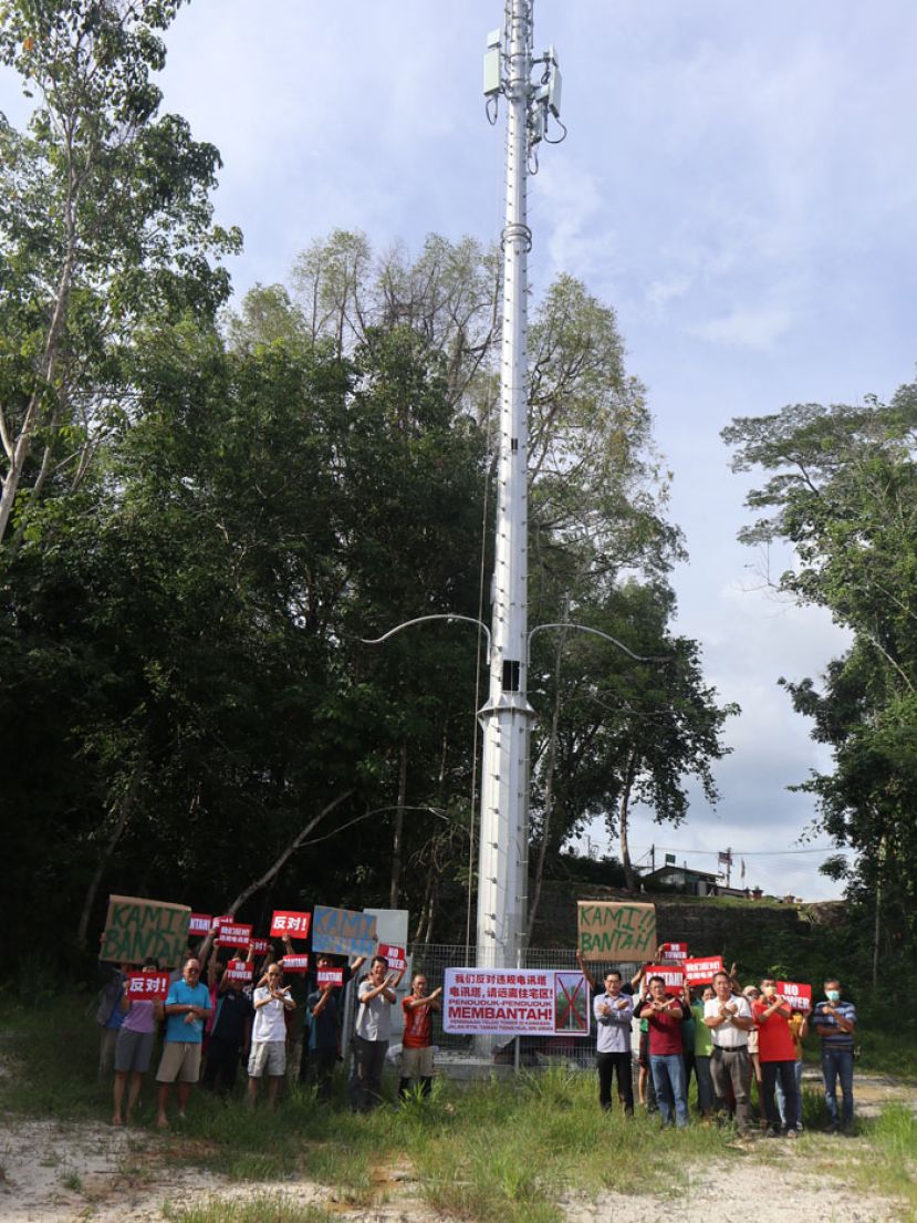 吴标生（右5）带领当地居民在已经完成的电讯塔前和平情愿，并展示&ldquo;反对手势&rdquo;。