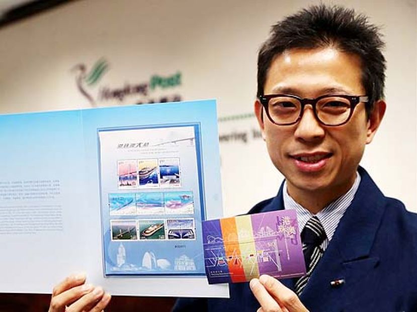 图示：香港邮政总局一名工作人员展示“港珠澳大桥”联合纪念套折和邮票小型张。
