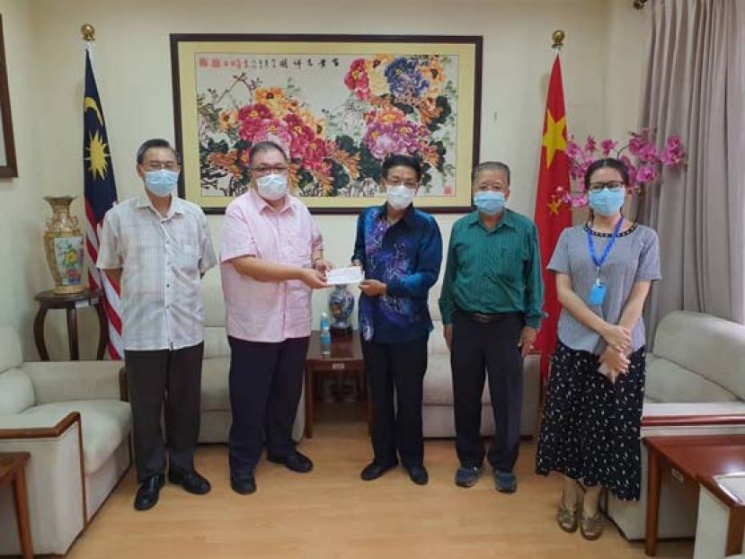中国驻古晋总领事程广中（右三）移交一万令吉支票予古晋中中校友会会长拿督黄国辉（左二）。