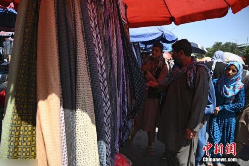 资料图：当地时间8月28日，阿富汗喀布尔市中心一集市，顾客在摊位上挑选商品。
