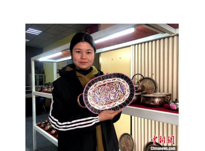 迪丽努尔&middot;艾则孜展示镶有艾德莱丝绸花纹的托盘。