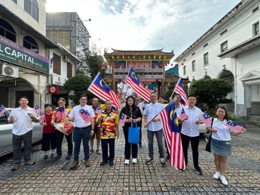联邦新闻局官员容巧妃（右5起）连同古晋老巴刹民众联谊会会长甲必丹林传政、秘书孙守生、黄笃荣市议员等人，于昨日配合916马来西亚日，在古晋老巴刹一带派发国旗予商家及民众；右4甲必丹杨国宗。