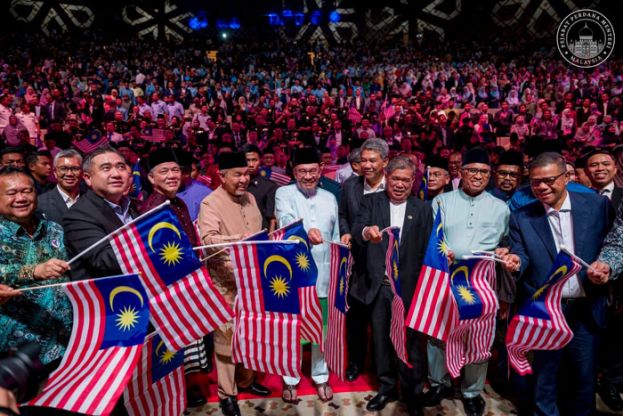 首相安华与一众部长在公务员例常集会上挥舞国旗。