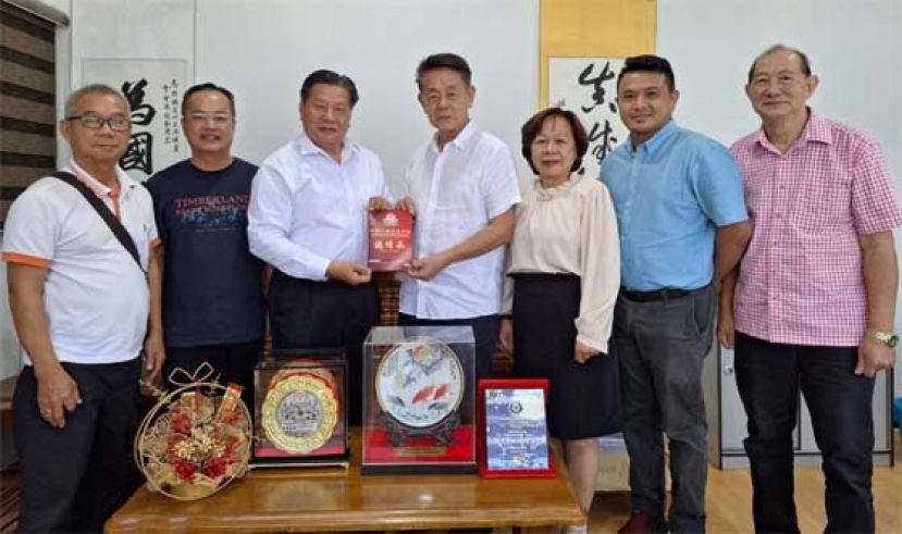 拿督陈冠勋（右4）由江宗兴（左3）手中接过中砂六桂堂新会所开幕任上宾邀请函；左起为江昌桦、翁新达；右起是龚招亨、龚久辉、甲必丹江丽訇。