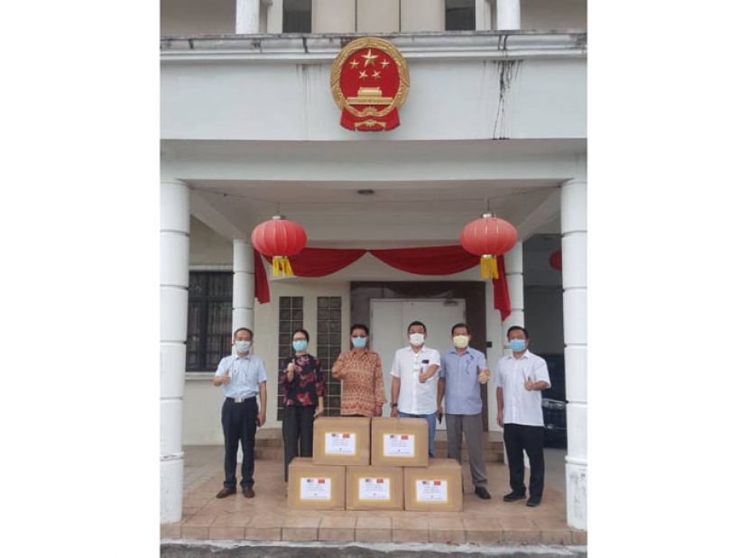 中国驻古晋总领事程广中（左三）移交1万个口罩给砂华总会长拿督黄良杰（右三）。