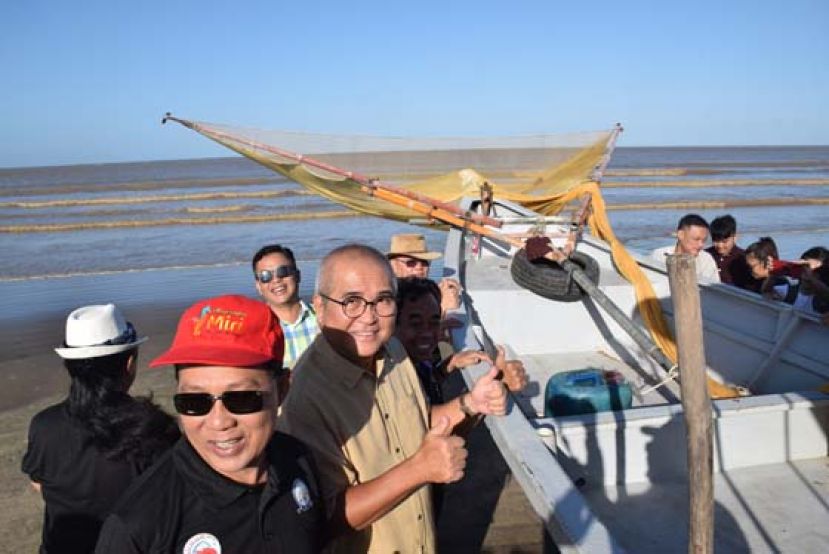 美里市长俞小珊(左2)与渔民携手将渔船推下海，准备亲身体验捕抓毛虾。