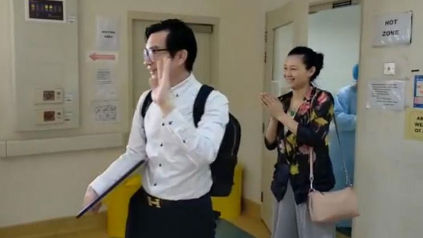 康复出院的中国夫妇向医护人员挥手，感谢他们的细心照顾。