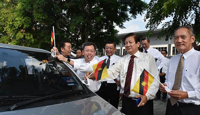 砂地方政府与房屋部长拿督沈桂贤（右四）配合722砂拉越日活动，派发砂拉越州旗予路过车主。