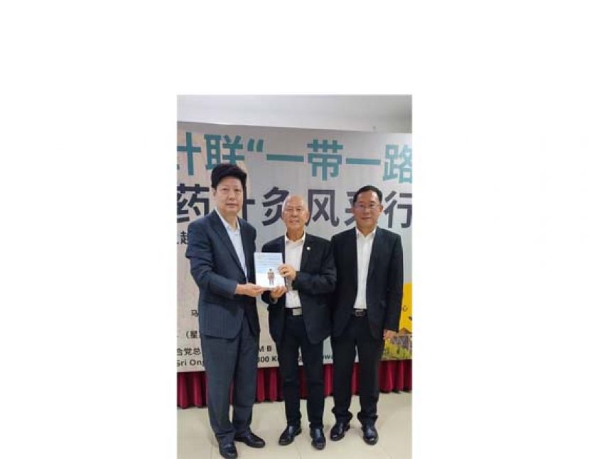世界针灸学会联合会秘书长杨金生（左）移交纪念品予砂旅游、创意产业局表演艺术部副部长拿督陈超耀时摄》右为中国驻古晋总领事邢伟平。