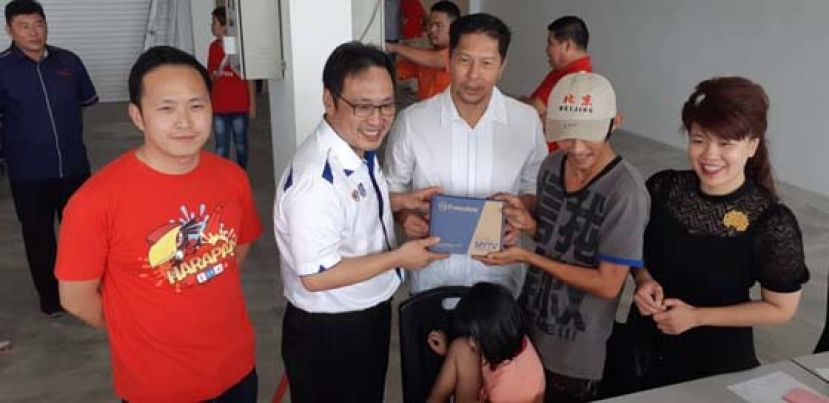 在行动党朋岭区州议员杨薇讳（右）以及特别助理江峰年（左）的陪同下，国内贸易及消费事务部副部长张健仁在派发电视解码器时攝。