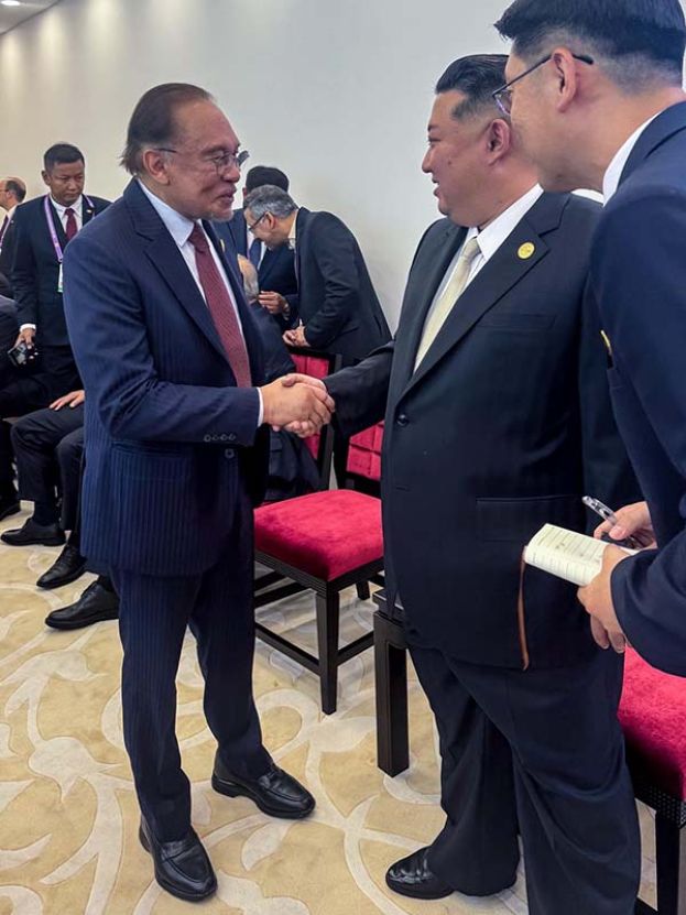 ●首相安华(左)与金正恩握手寒暄。