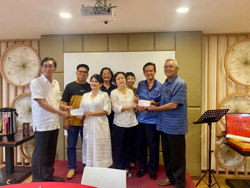 五哩八港中公校董会主席李仁赵(左一)及名誉主席蔡高井(右一)分别接收由王彩枝老师(左三)及蔡娜媚老师(右三)捐赠的3000令吉款项。左二为王彩枝老师夫婿容振林；右二为蔡娜媚老师之夫婿黄明永，后排左一为前校长吴一兰及校长许惠英。