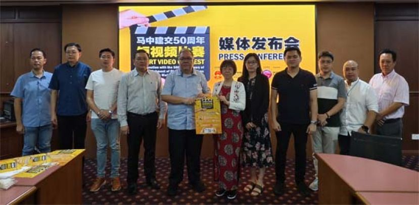 砂拉越中国友好协会常务副会长拿督黄国辉（左5）移交海报予中国驻古晋总领事馆副总领事宋长虹时影。