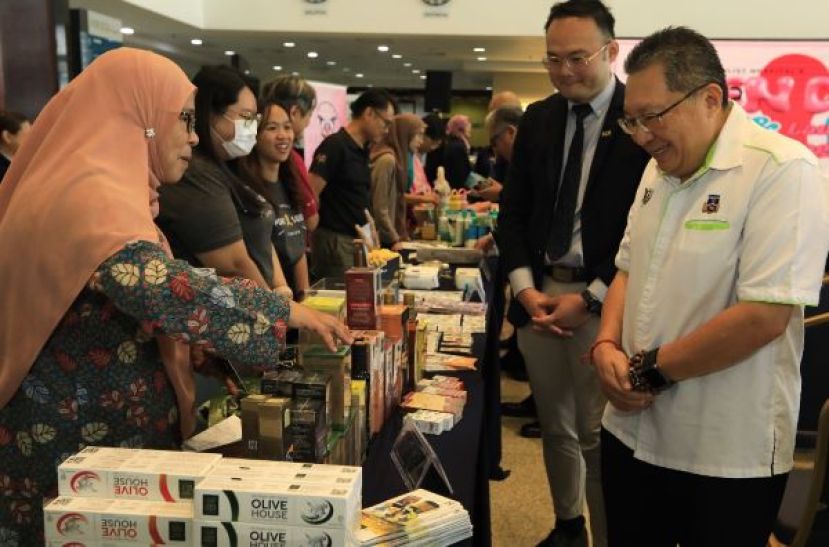 古晋专科医院医疗保健集团东马域首席执行员叶谨沛陪同南市市长拿督黄鸿圣（右）参观展示摊位时影。