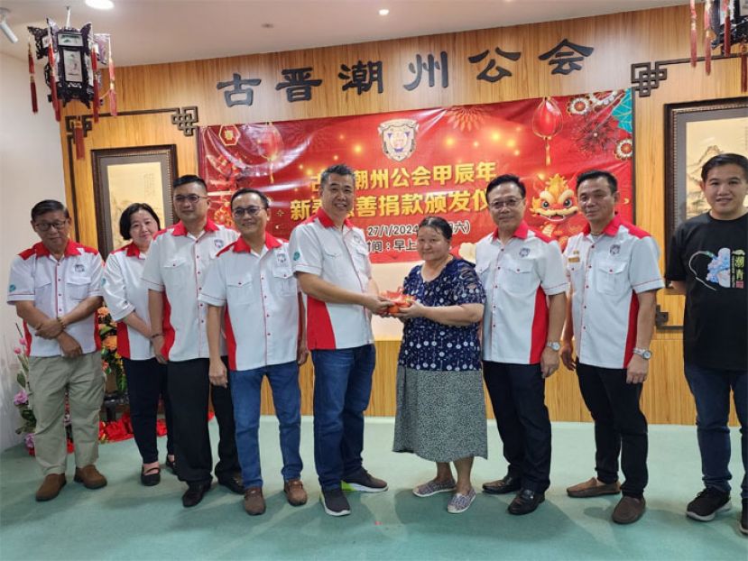 周文盛（中）在众执委陪同下，赠送新春礼品和红包予受惠者之一。左一起为该会文化股主任沈汉忠、妇女组主任郑姝萍、产业股主任卢少奎及第一副会长陈家福。右一及二分别是福利股主任陈实福和第二副会长陈瑞光。