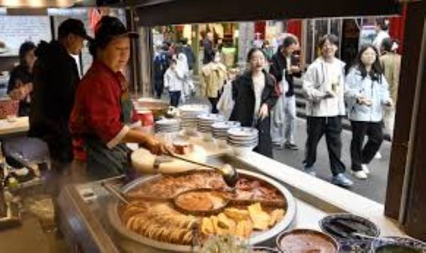 游客在北京烟袋斜街品尝美食。