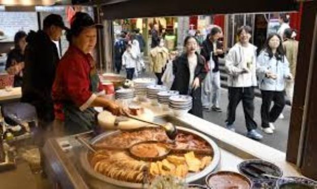 游客在北京烟袋斜街品尝美食。