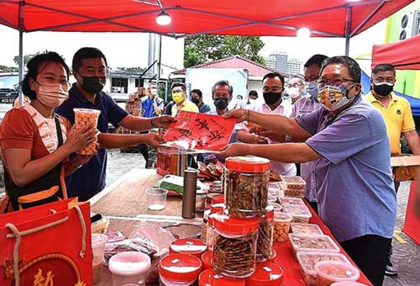 古晋南市市长拿督黄鸿圣派发年柑、春联、红包袋、口罩予摊位业者。